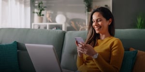 Woman looking at phone and smiling while on the couch