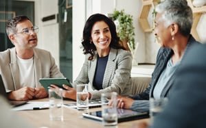 Business professionals collaborating in a conference room meeting with tablets and water glasses on the table.
