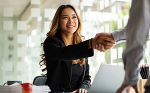 Professional woman smiling while receiving a handshake from a person